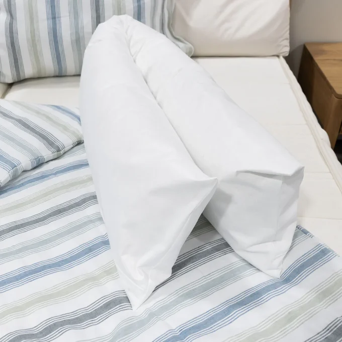 Housses anti-acariens traversin Softsan Protect Plus sur lit avec linge rayé