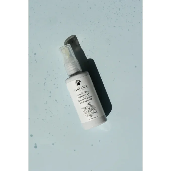 Odylique Huile de Massage Musculaire Bio – flacon incliné fond bleu clair avec éclaboussures